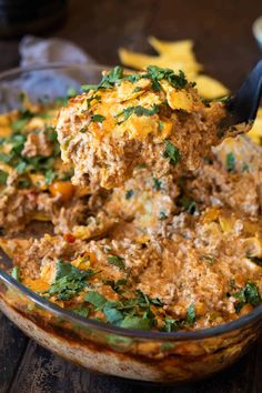 a spoon full of food sitting on top of a glass bowl filled with sauce and vegetables