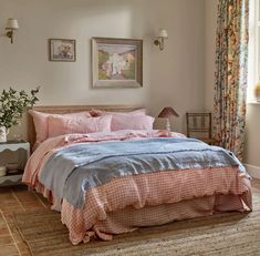 a bed with pink and blue comforters in a bedroom next to a painting on the wall