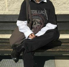 a young man sitting on top of a wooden bench