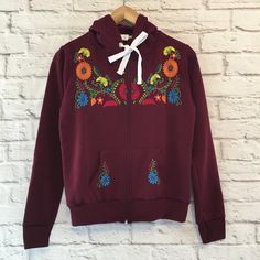 Women's Blue Floral Embroidered Mexican Sweatshirt Embroidered Mexican Hoodie With A Zipper - Sudadera Bordada Mexicana Made By Artisans In Chiapas, Mexico Color: Blue With Multi-Colored Embroidery Material: 50% Cotton & 50% Polyester Multicolor Embroidered Cotton Tops For Fall, Hooded Cotton Tops With Embroidered Graphics, Embroidered Cotton Hoodie For Spring, Traditional Fall Tops With Embroidered Hem, Hooded Tops With Machine Embroidery For Winter, Spring Embroidered Cotton Hoodie, Traditional Embroidered Hem Tops For Fall, Winter Cotton Hoodie With Floral Embroidery, Traditional Cotton Tops With Contrast Embroidery