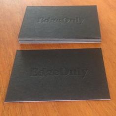 two black business cards sitting on top of a wooden table