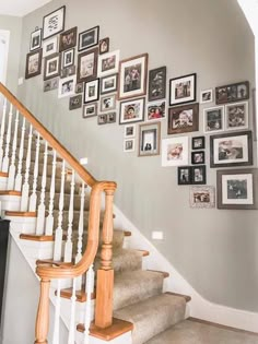 a staircase with many pictures on the wall and wooden banisters in front of it