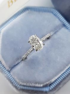 a diamond engagement ring sitting on top of a blue velvet box