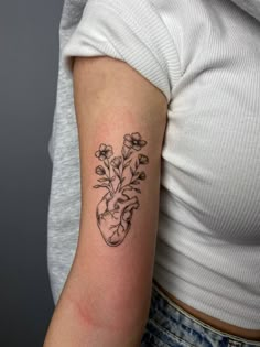 a woman's arm with a heart and flowers tattoo on the left side of her arm