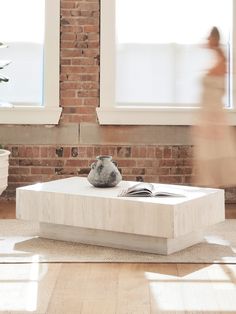 a woman is walking past a sculpture in the middle of a room with brick walls