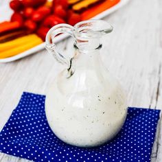 a small glass bottle sitting on top of a blue napkin next to a plate of vegetables