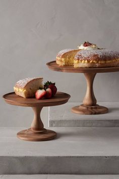 two cakes on pedestals with strawberries and powdered sugar sitting on top of them