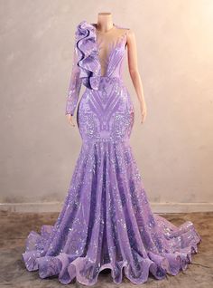 Dazzle everyone at your prom with this exquisite lavender gown, designed to make you shine. Have you ever seen a dress that combines elegance and boldness so effortlessly? The elaborate sequin patterns catch the light beautifully, creating a mesmerizing effect as you move. The one-shoulder design, accentuated with a dramatic ruffle, adds a contemporary twist to the classic mermaid silhouette. The fitted bodice highlights your figure, while the flared skirt ensures you glide across the dance floor with grace. The sheer panel at the neckline adds a modern touch, giving the dress a hint of sophistication and allure. Crafted with precision and care, this gown promises both comfort and a perfect fit, ensuring you look and feel your best all night long. Whether you're attending prom, a formal ev Purple Sparkly Prom Dress, Sleeved Prom Dress, Purple Mermaid Dress, Prom Dress With Ruffles, Lavender Gown, One Shoulder Prom Dress, Long Sleeve Sequin Dress, Purple Mermaid, Purple Prom Dress