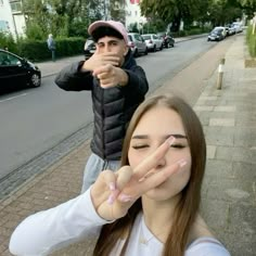 two people standing on the side of a road with their hands in front of them