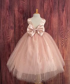 Our enchanting Ankle Length flower girl dresses are sure to turn heads! Bodice is made of Blush satin, waist consists of a matching sowed in sash (NOT DETACHABLE) The back of the dress has an open deep V-Back with a hidden zipper, followed by a detachable bow. The skirt has 4 tulle layers for fullness, the top layer of tulle consists of pearls. The dress has 2 layers of lining with crinoline. This dress is perfect for any occasion!  Dress Is Pictured with a petticoat NOT INCLUDED https://www.etsy.com/listing/1305138635/white-ankle-length-petticoat-wedding?click_key=50d449c187c9e82c565249da914d7ed38b32b9f7%3A1305138635&click_sum=17db9314&ref=shop_home_active_2 Visit our store, more items to come!  https://www.etsy.com/shop/LittledarlnBoutique?ref=profile_header CUSTOM MEASUREMENTS AVAILABLE Pink Tulle Ball Gown For First Communion, Princess Style Satin Ball Gown For Pageants, Elegant Pink Ball Gown For First Communion, Princess Style Satin Ball Gown, Pink Tulle First Communion Dress, Pink Sleeveless Tutu Dress For First Communion, Princess Style Satin First Communion Dress, Satin Princess Dress For Dress-up, Fitted Princess Dress With Satin Bow For Bridesmaids