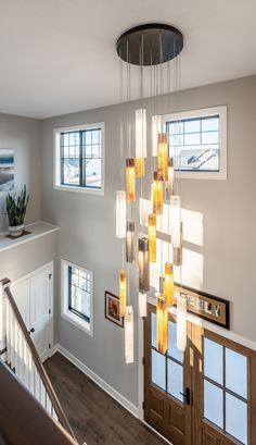 a modern chandelier hanging from the ceiling in a living room with wood flooring