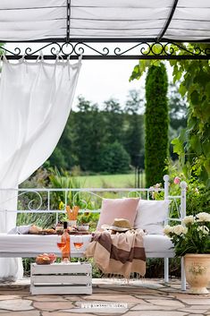 a white bench sitting in the middle of a lush green park next to flowers and trees