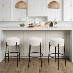 two stools in front of a kitchen island with white cabinets and counter tops,