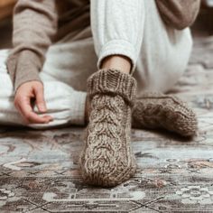 a person sitting on the floor with their feet up wearing knitted socks and slippers