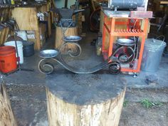 there is a metal thing on top of a tree stump in the shop with other tools