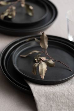 two black plates sitting on top of a table next to a glass filled with water