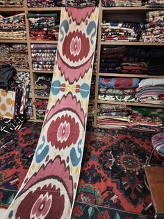 a colorful carpet is on display in a store with other rugs and fabrics behind it