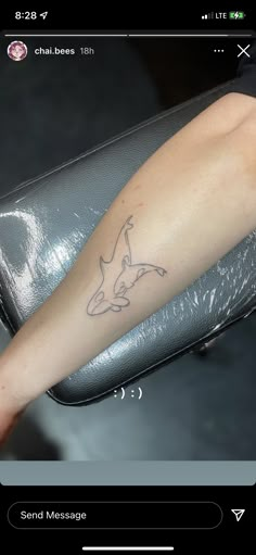 a small tattoo on the arm of a woman's left leg, with a dolphin