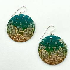 two circular earrings with green and gold designs on them, hanging from silver earwires