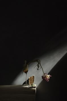 a vase with some flowers sitting on top of a wooden table next to a wall