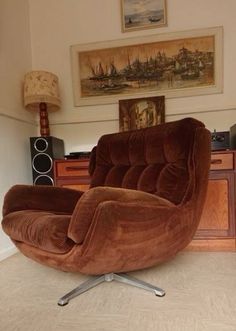 a large brown chair sitting in a living room next to a wall with pictures on it