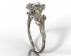 "A dainty 14k white gold ring showing a lotus set with a beautiful diamond or moissanite for your choice. The lotus is surrounded by a composition of leaves giving the ring a very natural look. ★See A Video Of This Amazing Ring Here★ https://youtu.be/WDBLPTtTrnQ Details: SKU: Fle39ww Gem Details: Center Gem: Choose between Moissanite or Natural diamond. Carat Weight: Choose from the \"Weight\" button Color/ Clarity: Moissanite - Forever One 'Charles & Colvard' arrive with the warranty certif Elegant White Gold Solitaire Flower Ring, Elegant Wedding Flower Ring With Single Diamond, Elegant Flower Ring With Single Diamond, Lotus Flower Ring Engagement, Flower Ring Engagement, Gold Ring Flower, Lotus Flower Engagement Ring, Engagement Ring Flower, Nature Wedding Ring