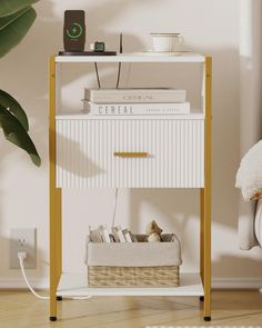 a white and gold shelf with books on it next to a plant in a room