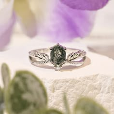 Make every stare worthwhile with our Calla Lily Moss Agate Ring. This ring features an oval-cut moss agate gemstone in a nature-inspired curved split band. A brilliant piece that shines elegantly, this ring is anything but ordinary.  *Please be informed that your moss agate patterns are naturally distinct and unique from the portrayed picture, and you will never witness the same pattern in two gems. It is one of a kind with a unique story that only you can tell. Made in 14K white gold vermeil (1 Calla Lily Engagement Ring, Lily Moss, Agate Wedding Ring, Crystal Engagement Rings, Moss Agate Jewelry, Agate Wedding, Nature Inspired Engagement Ring, Dream Rings, Gold Promise Rings