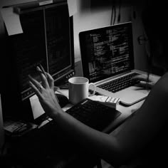 a person sitting at a desk with two laptops and a coffee cup in front of them