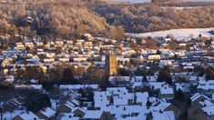 a city with lots of snow on the ground and hills in the background, surrounded by trees