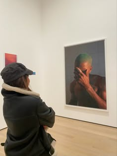 a woman sitting on the floor in front of an art work with her hands to her face