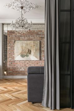 a living room with a couch, chair and brick wall in the background that has a chandelier hanging above it