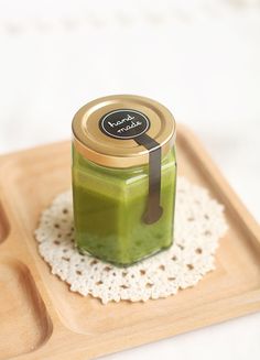 a green smoothie in a glass jar on a wooden tray with a lace doily