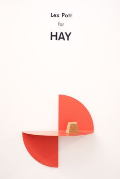 a red shelf sitting on top of a white wall next to a sign that says alex pott for hay