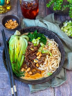 a bowl filled with noodles and vegetables next to chopsticks