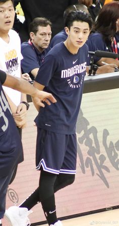 two young men playing basketball in front of a group of people watching them from the sidelines