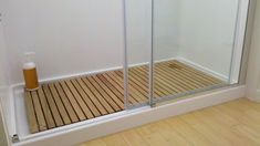 a bathroom with wooden flooring and a glass shower door next to a white wall