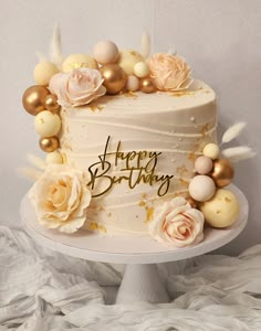 a birthday cake decorated with gold and white flowers