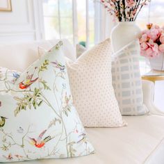 three pillows on a couch with flowers in the background