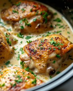 three pieces of chicken in a white sauce with parsley on the top and bottom