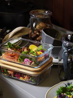 two plastic containers filled with food sitting on top of a counter next to other dishes