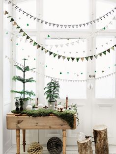 a wooden table topped with plants next to a window covered in bunting and garland