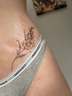 a woman's stomach with a flower tattoo on the side and words written below it