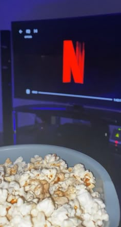 a bowl filled with popcorn sitting on top of a table next to a tv set