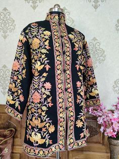 Get Customizable Kashmiri Jacket With Multi-colour Embroidery A Kashmiri Jacket with All Over Multicolour Aari Embroidery (Front & Back) This Kashmiri jacket Makes you stand apart with its vivid colours and Floral embroidery, The base colour is BlackWith Multicolor Aari Embroidery is done all over the jacket, the material used is of high-quality Pure wool and the embroidery is done by brilliant Kashmiri artisans. Embroidery : Aari Work Length : 35 Inches (101.6cms) [Customizable] Fabric :100 per Embroidered Stand Collar Kurta For Winter, Traditional Bandhgala With Floral Embroidery And Stand Collar, Festive Traditional Outerwear With Dabka Work, Winter Kurta With Embroidered Stand Collar, Traditional Zari Work Wear For Fall, Traditional Embroidered Bandhgala With Stand Collar, Bollywood Style Outerwear With Chikankari Embroidery, Traditional Nehru Jacket With Multicolor Embroidery For Winter, Traditional Embroidered Nehru Jacket For Fall