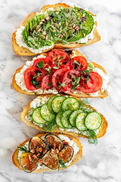 four slices of bread topped with cucumbers, tomatoes and other toppings on top of white marble