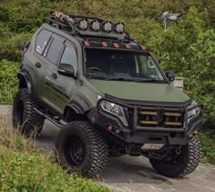 an off road vehicle parked on the side of a road near some bushes and trees