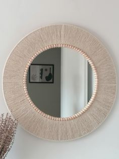 a round mirror hanging on the wall next to a vase