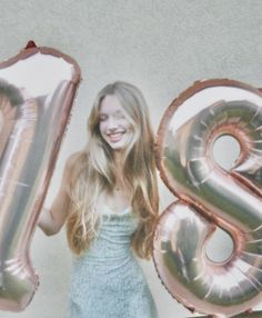 a woman holding two large balloons in front of her face and the number 8 on it