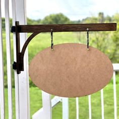 a wooden sign hanging from the side of a white porch with grass in the background